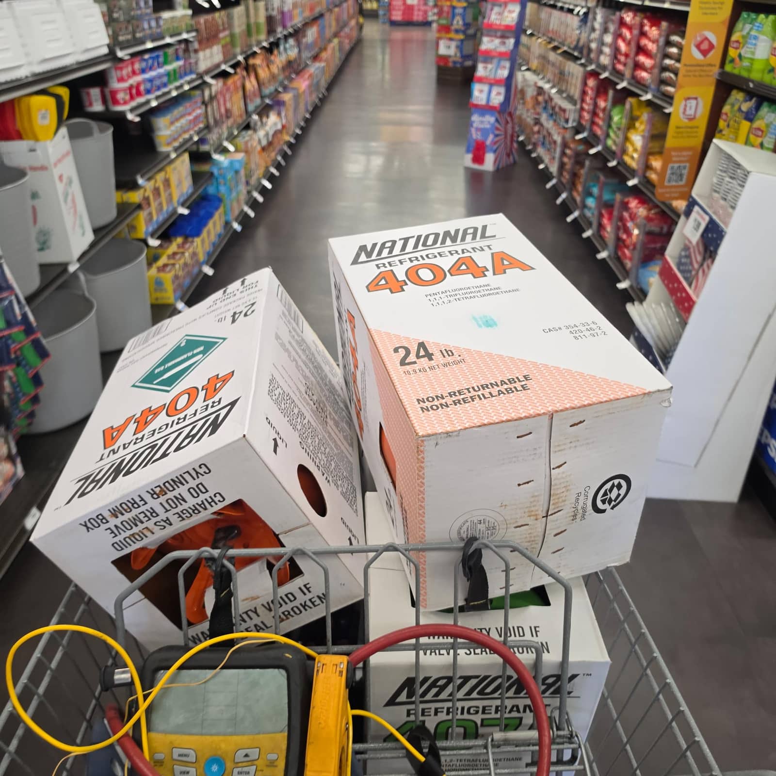 Service cart loaded with refrigerant cylinders alongside manifold gauges and a clamp meter